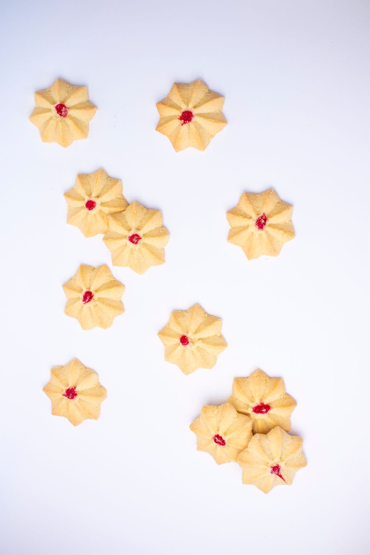 Flower-shaped butter cookies with red centres on a white surface